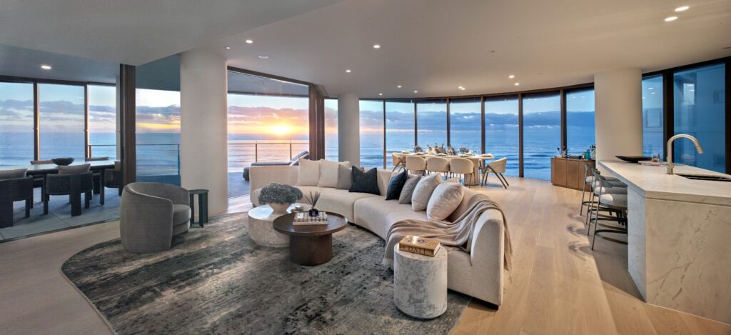 Interior image of a beachfront living and dining space showcasing open-plan design and full-height glazing with ocean views.